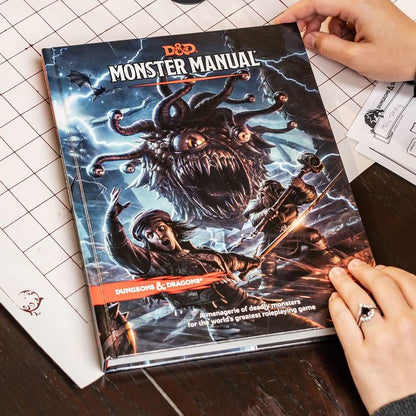Dungeons & Dragons Monster Manual 5E hardcover book shown at table with dice